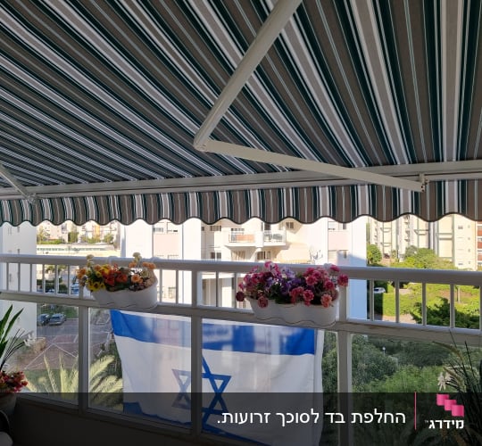 סוכך פסים ירוק לבן במרפסת עם פרחים